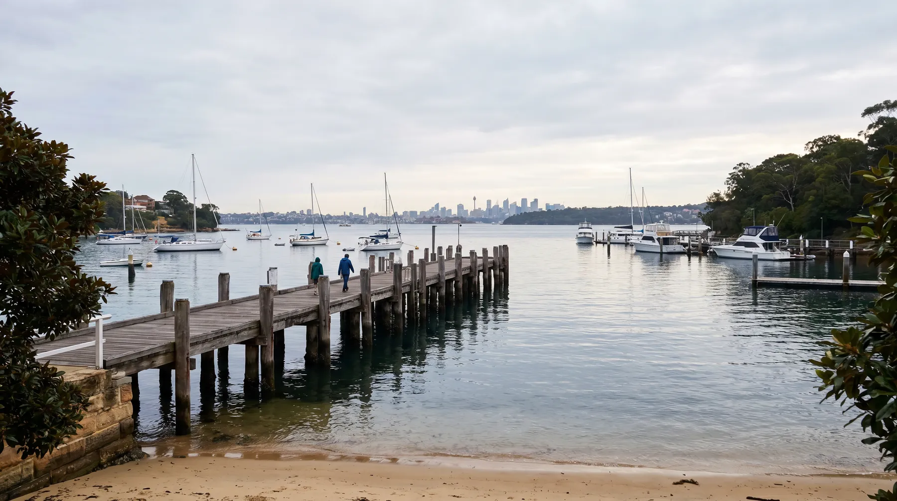 The timber ferry wharf at Woolwich reaching into the harbour, yachts moored, city skyline distant